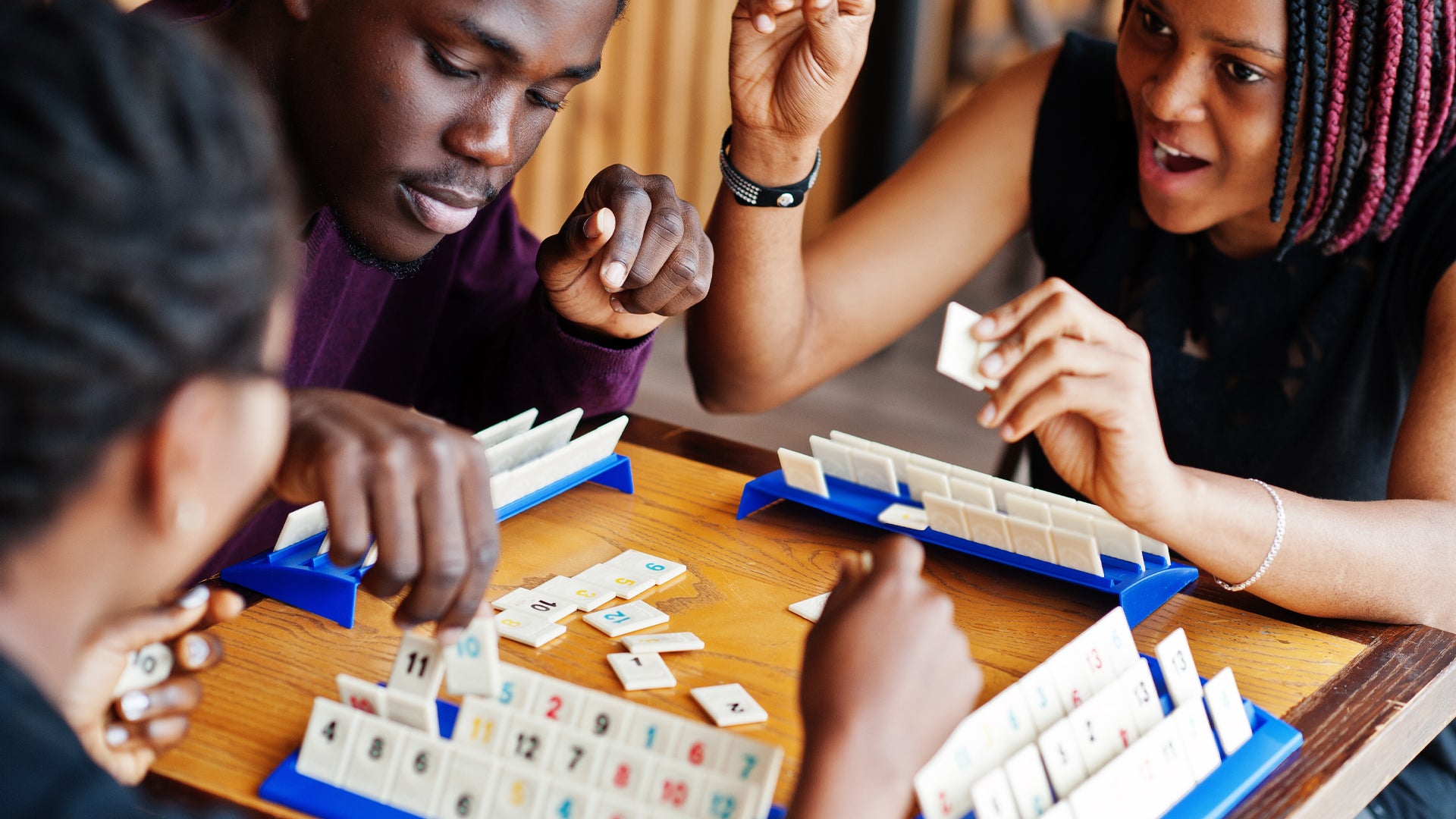 A group of adult friends playing the board game Rummikub