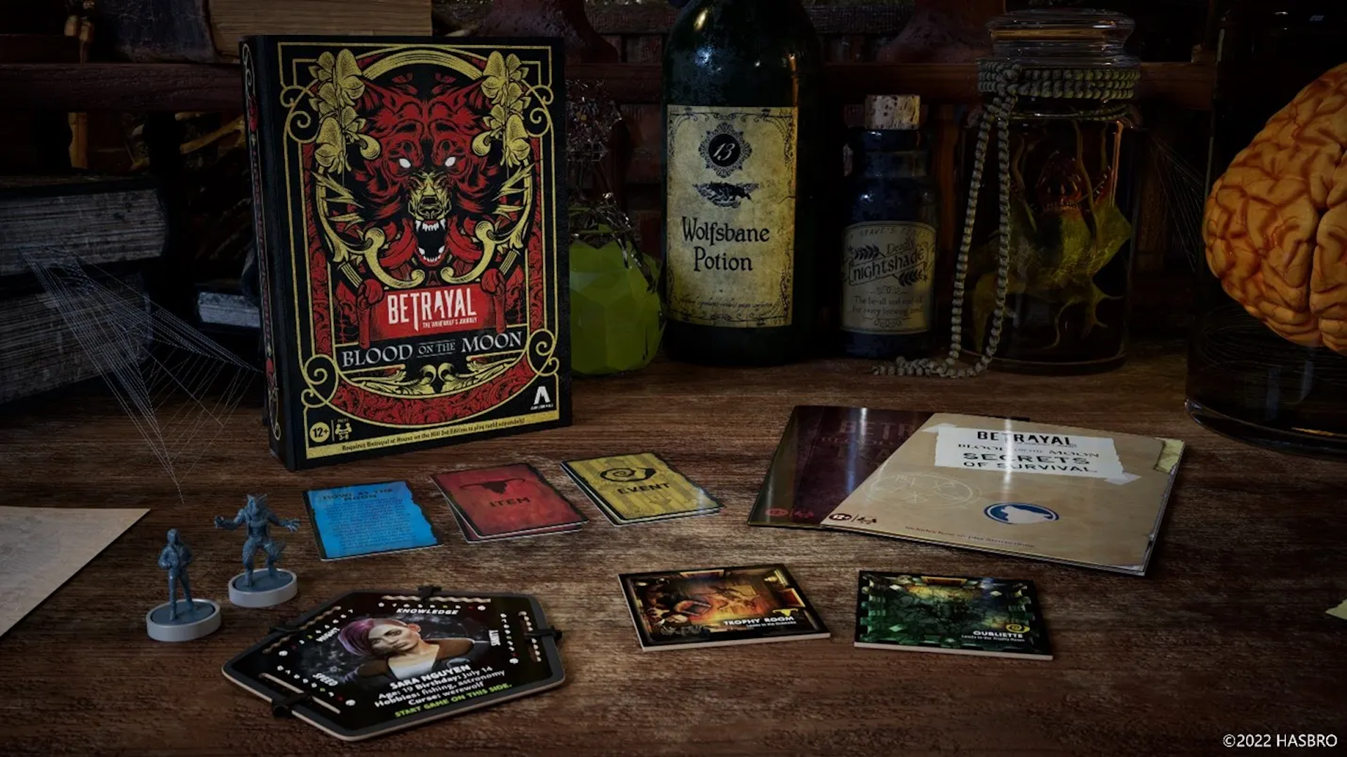 A promotional shot for Betrayal at House on the Hill's first expansion, The Werewolf’s Journey: Blood on the Moon. It shows off the new components and the box, which has a snarling wolf's head in crimson red and gold.