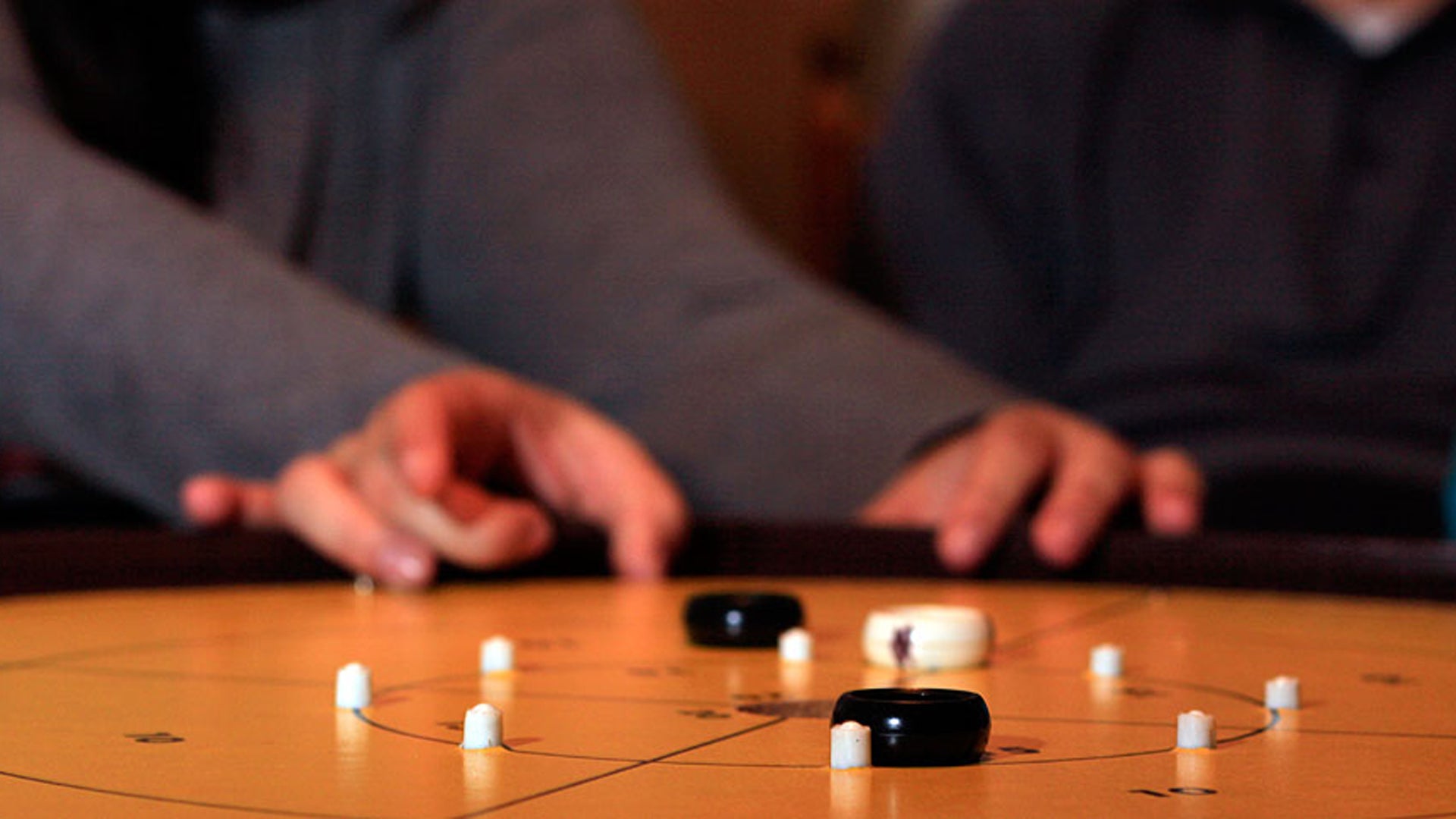 A player takes a shot in dexterity game crokinole